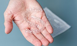 person holding two Invisalign aligners