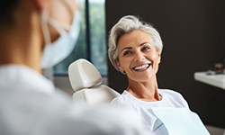 Beautiful senior female dental patient smiling at her dentist