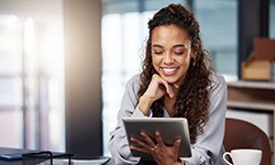 Woman smiling while looking at tablet at work