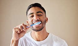 Man smiling while brushing his teeth