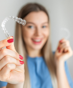 Woman in blue shirt holding clear aligners